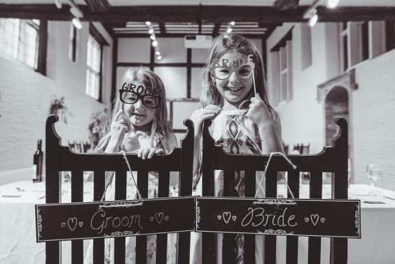 Two young children at a wedding holding bride and groom glasses