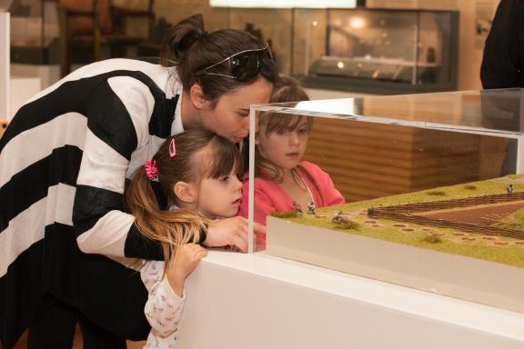 A mother and two daughters looking into a glass display cabinet