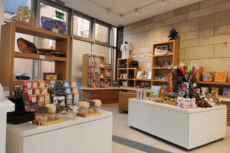 A gift shop in a Civil War Centre with two white stands and wooden shelves featuring gifts to purchase.