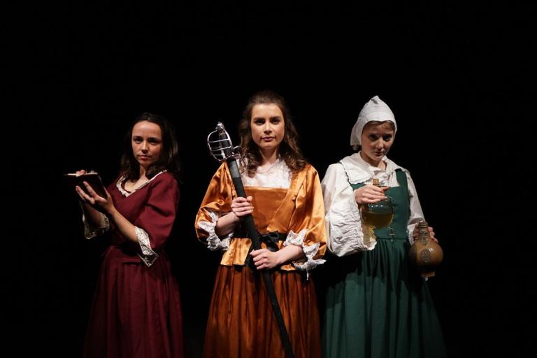 Three ladies in a yellow, red and green dress each holding a book, sword and glass.