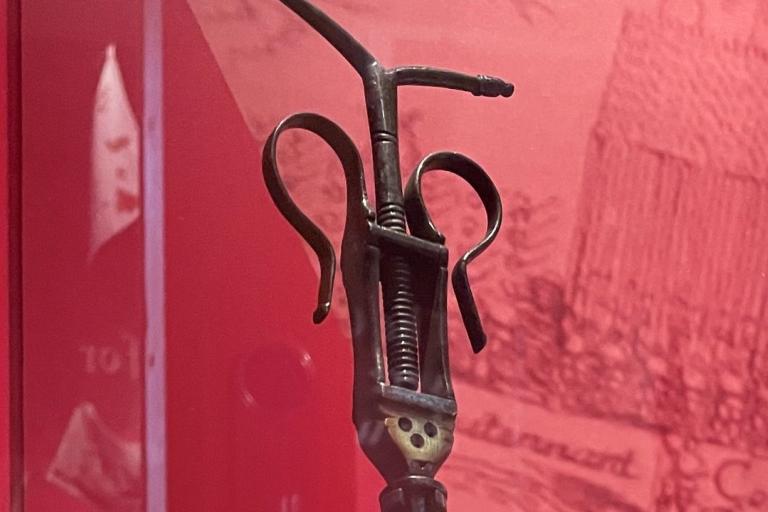 A steel bullet extractor in a display case in a gallery.