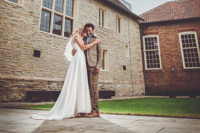 A bride and groom on their wedding day standing outside 