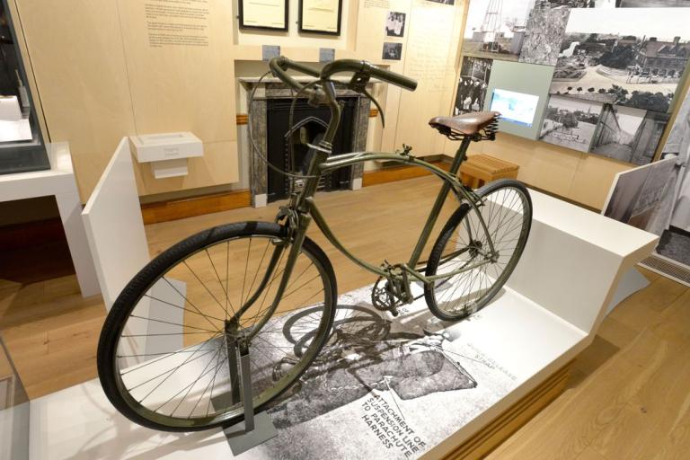 A green folding parachute bike used during World War II displayed in the gallery.