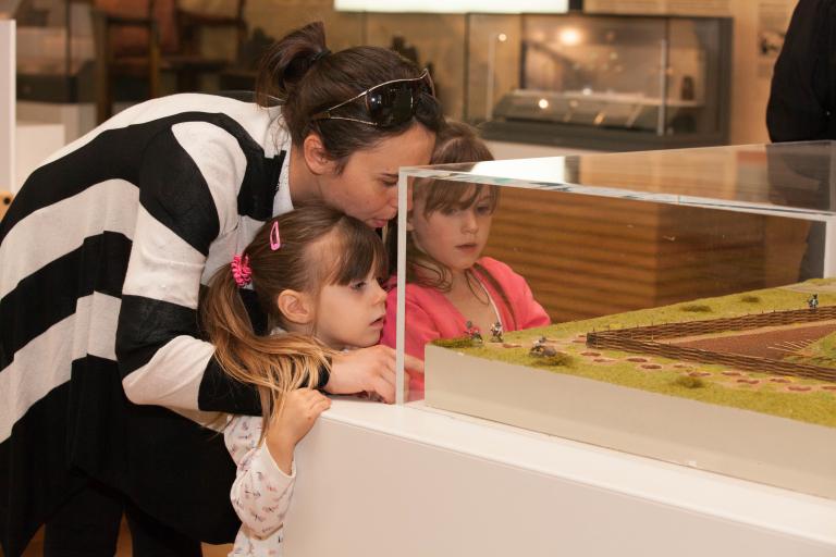 A mother and two daughters looking into a glass display cabinet