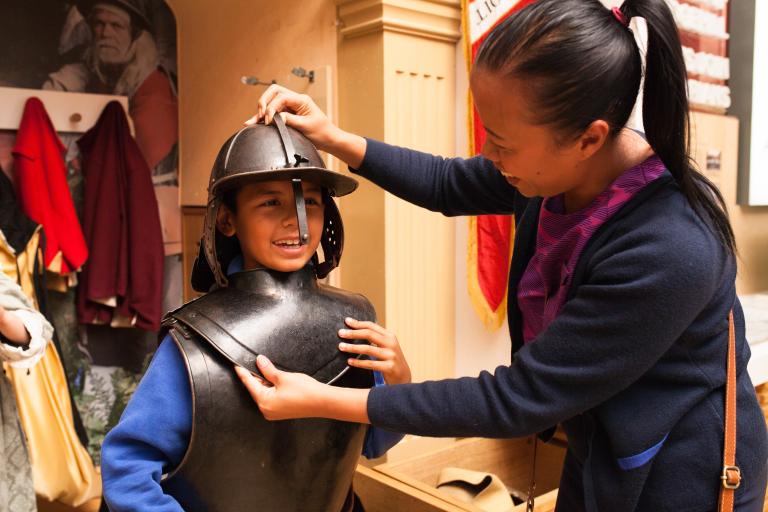 Mother with child trying on suit of armour