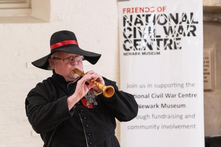 Man dressed up in Civil War clothes playing an instrument 