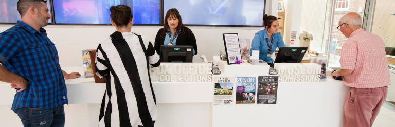 Three customers buying tickets from two members of staff at the National Civil War Museum 