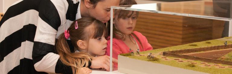 A mother and two daughters looking into a glass display cabinet